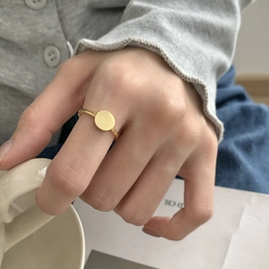 Close-up of a minimalist gold circular ring worn on a finger in a lifestyle setting
