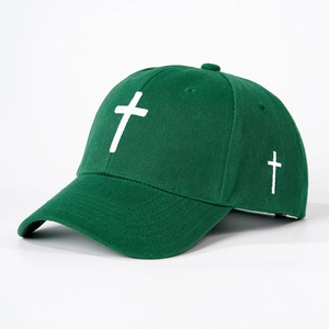 Detailed embroidery of a white cross on a dark green cotton baseball cap fabric