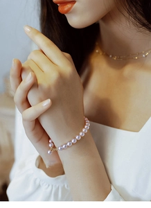 Detail of lavender pearl bracelet with gold clasp worn on wrist for French vintage style