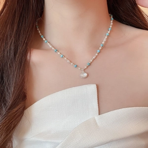 Dettaglio del ciondolo ovale in opale su collana di perle bianche e perle turchesi