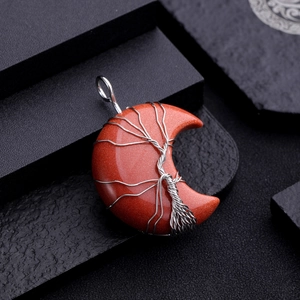 Macro view of crescent moon pendant with red goldstone and silver wire tree of life wrap