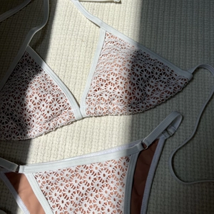 Detail of white crochet bikini with hollow lace pattern and skin-tone lining