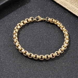 Close-up of golden stainless steel box chain bracelet with secure lobster clasp on black background