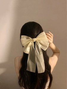 Detail of a large cream organza hair bow clip on wavy hair for an elegant look