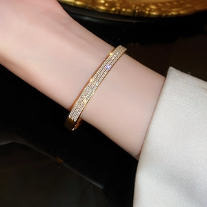 Dettaglio del bracciale placcato oro con tre file di zirconi micro-pave sul polso di una modella