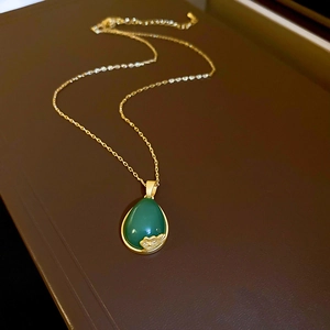 Detailed close-up of dark green teardrop pendant with gold flower relief and chain