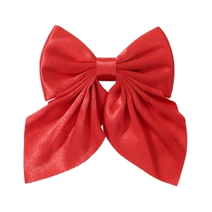 Detailed close-up of a large red satin bow hair clip with smooth glossy fabric texture