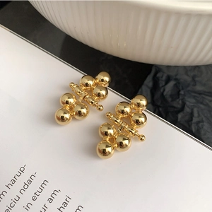 Detail shot of 925 silver needle golden bead earrings with shiny metallic spheres
