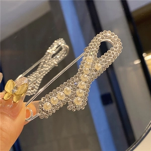 Detail of silver safety pin brooch with white rhinestones and pearls for waist adjustment