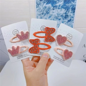 Close-up of sparkling rhinestone fruit hair clips with heart and crown designs for kids