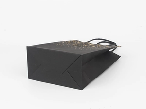 Detail of premium black paper gift bag showing the sturdy folded bottom and gold speckle design