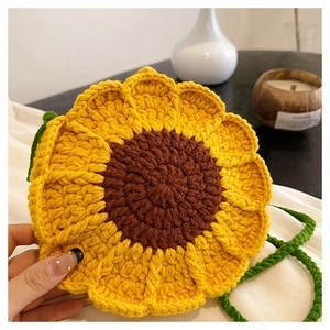 Detail of handmade knit sunflower crossbody bag with yellow petals and green strap