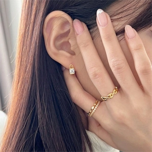 Close-up of gold padlock earrings with square zircon and layered chain rings for women