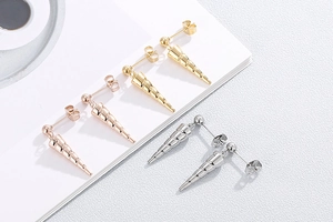 Detailed view of cone shaped stud earrings in gold, rose gold and silver finishes