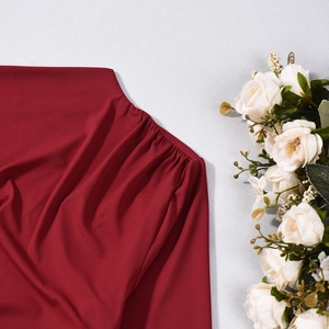 Close-up of pleated deep red fabric with fine plain weave texture and rich burgundy tones