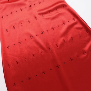 Close-up of red satin dress fabric featuring intricate rhinestone and beadwork details