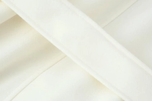 Detailansicht der weißen Wollstofftextur und feinen Nähte auf dem Gürtel