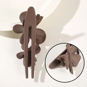 Detail view of brown flower hair clip showing matte texture and metal spring mechanism