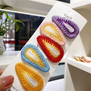 Macro view of five colorful hand-knitted embroidery drop-shaped BB hair clips on a card