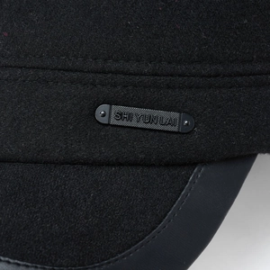 Detail of wool fabric texture and leather brim on men's winter flat top cap with metal tag