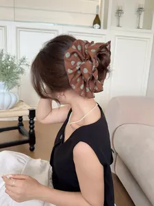 Detail of a large brown polka dot chiffon scrunchie with soft pleated texture and volume