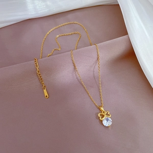 Detail of gold bow necklace featuring a sparkling round crystal on soft fabric
