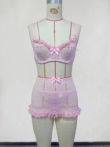 Detailed view of pink floral lace fabric with ruffled edges and satin bow on lingerie set
