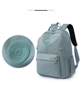 Detail of light blue nylon backpack showing zippered compartments and brand logo