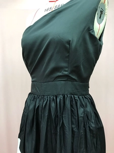 Detail of dark green one-shoulder satin dress featuring elegant waist seams and pleated skirt