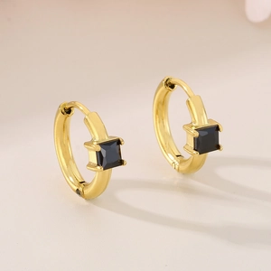 Detail of gold hoop earrings with square black cubic zirconia in a minimalist style