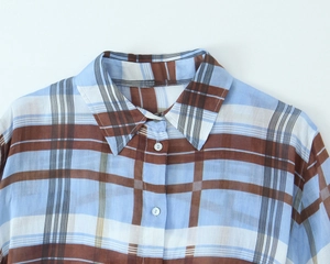Detailed close-up of the collar and button-down front of a blue checkered linen shirt