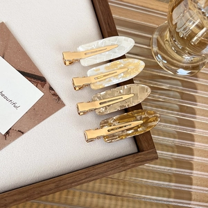 Detail of four colorful marble pattern seamless hair clips with golden metal base