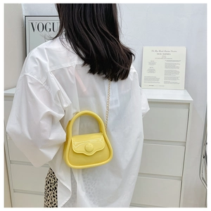 Mini yellow jelly bag with glossy finish and gold chain shown on a fashion model