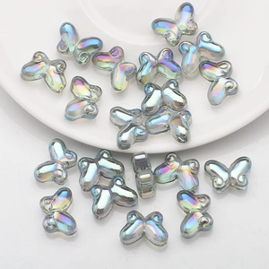 Macro view of 10x14mm iridescent butterfly glass beads on a white ceramic plate edge