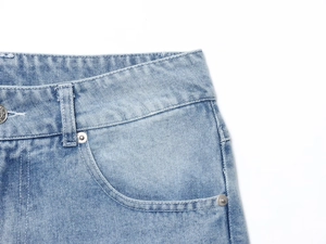 Close-up detail of light blue denim jeans showing stitching, waist belt loops and metal rivets