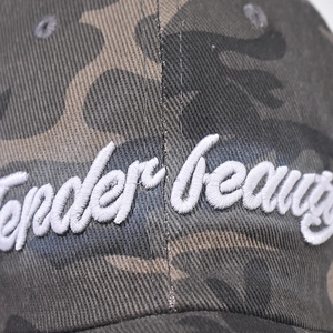 Gros plan sur la broderie 3D blanche 'Tender beauty' sur une casquette camouflage