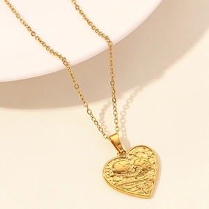 Detail of 18k gold heart pendant featuring romantic skull embossing on fine chain