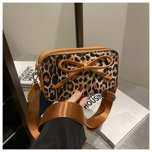 Detail of leopard print crossbody bag with brown leather bow and wide strap