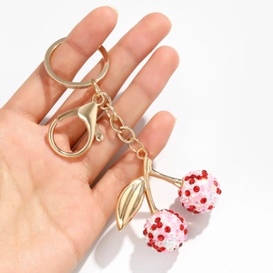 Porte-clés cerises rouges étincelantes avec feuilles dorées et strass sur fond blanc