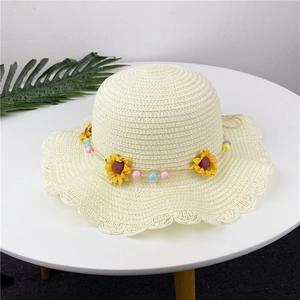 Detail of hand-woven straw hat featuring wavy brim and yellow sunflower decoration