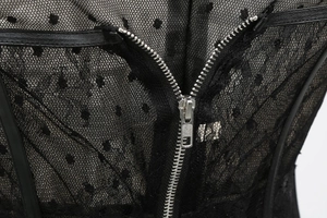Detail of silver metal zipper on black mesh fabric with polka dot texture and lace