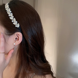 Dettaglio di un elegante cerchietto con cristalli a forma di foglia su una modella
