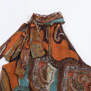 Close-up of bohemian paisley print top with metallic gold thread and ruffle tie details