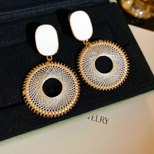 Close-up of bohemian dreamcatcher earrings with white weave and golden hoops
