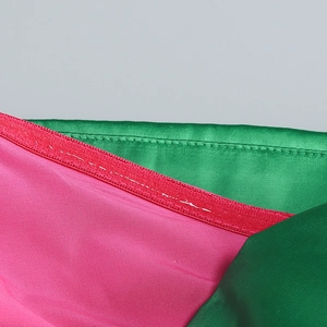 Detailed close-up of green and magenta satin dress fabric with premium stitching