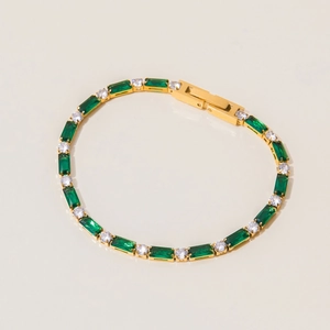 Detail of gold chain bracelet with emerald green stone and white cubic zirconia accents