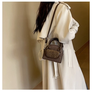 Brown suede handbag featuring plush shearling trim detail worn with a beige trench coat