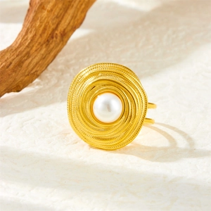 Golden spiral textured stainless steel ring featuring a white pearl on a wooden background