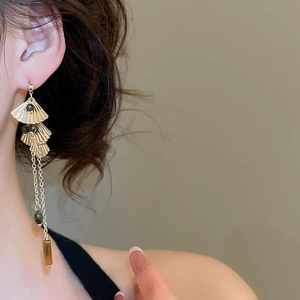 Detail of tiered ginkgo leaf tassel earrings with dark beads on a model