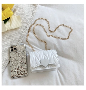 Detail view of mini white heart crossbody bag with gold chain and quilted texture